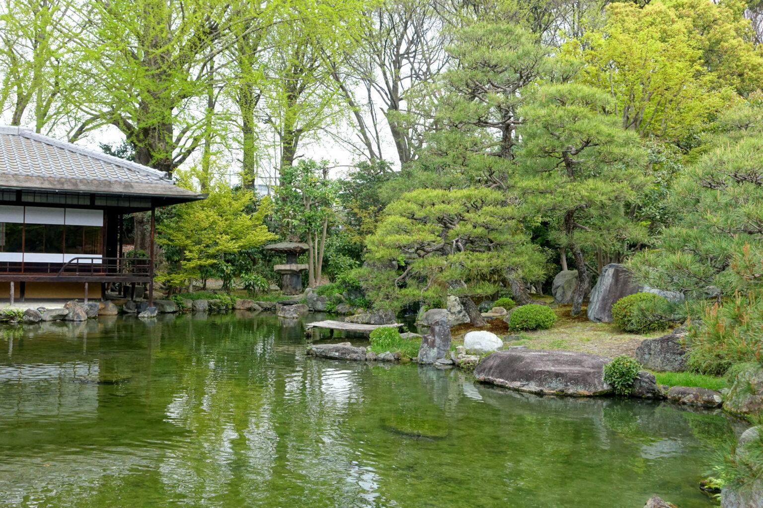 渉成園の印月池と滴翠軒。池のまわりに木々が茂る昼の庭園